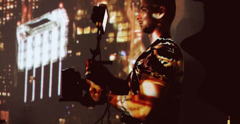 Person filming with city lights background.