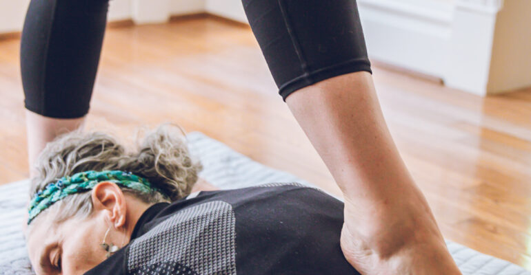 Person lying on floor receiving a foot massage indoors.
