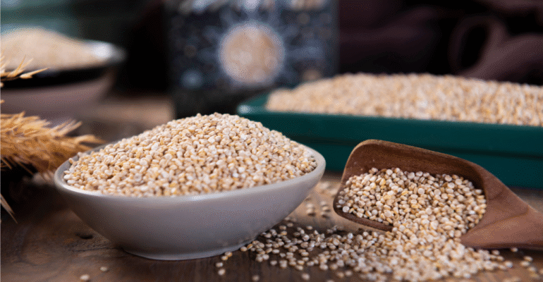 Bowl and scoop of quinoa on table.