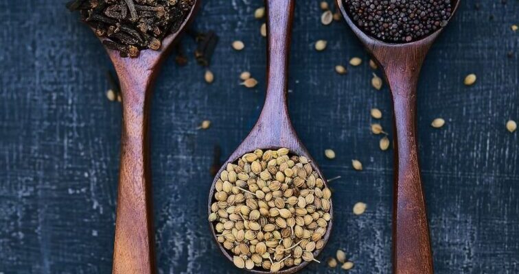 Wooden spoons with assorted spices on slate.