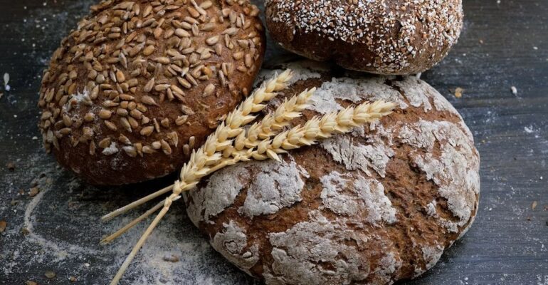Assorted artisan breads with wheat stalks.